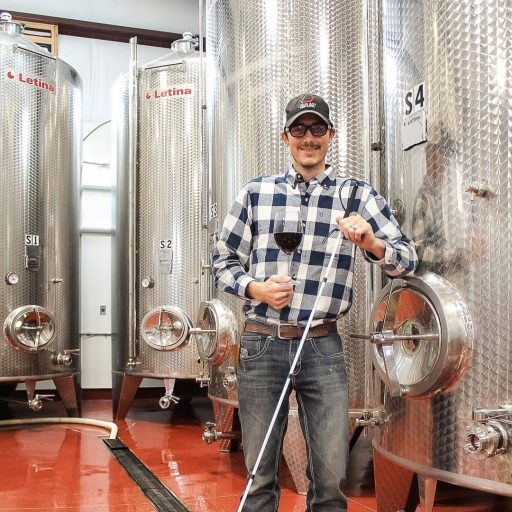 Man leaning on one of his Letina wine tanks in the Liquid Art Winery in Kansas, USA.