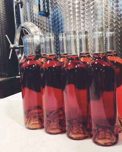 Bottles of wine in front of a Letina wine tank in the Liquid Art Winery in Kansas, USA.