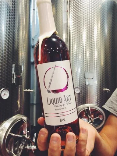 Bottle of wine in front of wine fermenters in Liquid Art Winery in Kansas, USA.