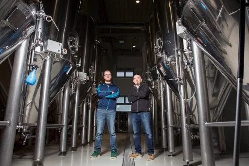 Men posing for a photo in front of the conical fermenters in the Varionica brewery in Croatia.